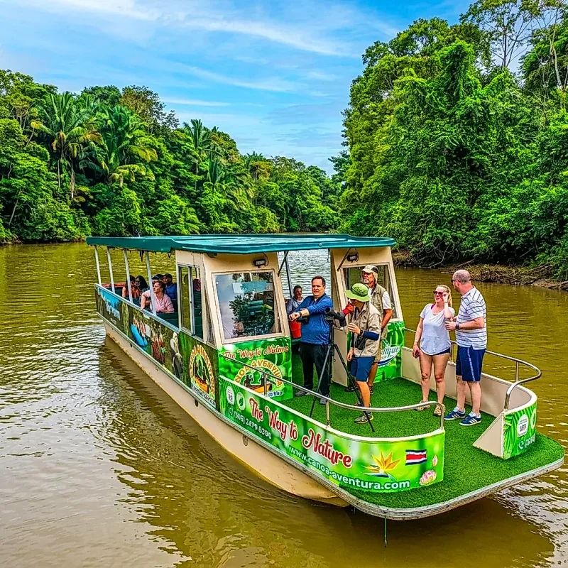 Tourists in a boat admiring nature under a blue sky in the Caño Negro Wildlife Refuge.